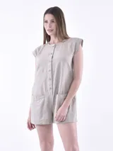 Monoprenda (romper) de color rojo, sin mangas, con cuello redondo y cierre frontal de botones. Presenta bolsillos delanteros a la altura de la cadera y un corte holgado.