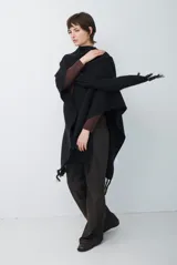 Ruana de tejido de punto en color negro, con diseño de cuello alto y terminaciones con flecos en los bordes.