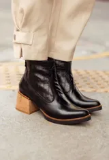 Botas cortas de cuero negro con detalle de punta fina redondeada y taco cuadrado de madera.