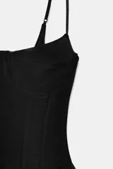Corsé de escote recto con tirantes finos ajustables, confeccionado en tul negro. Presenta estructura de varillas y bajo con detalle de volantes.