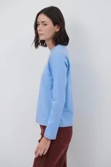 Remera de manga larga color marrón, con costuras a la vista en color blanco que resaltan los cortes de la prenda. Presenta un pequeño bordado blanco en la parte inferior y un corte recto.