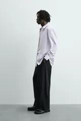 Camisa slim fit blanca con rayas verticales finas en color gris, confeccionada en tejido de algodón. Presenta cuello italiano y manga larga con puño abotonado. Cierre frontal con botonadura.