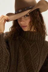 Polera de tejido de punto con diseño de ochos y detalles de tientos en contratono en las mangas. Presenta cuello alto y corte cropped.