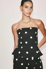Mono largo de escote recto sin tirantes, con peplum en la cintura, perneras acampanadas y estampado de lunares.