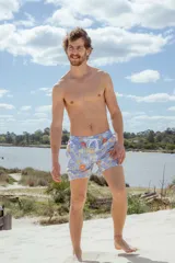 Short de baño celeste con estampado de flores y hojas en tonos naranja, amarillo y verde. Cuenta con cintura elástica y cordón ajustable.