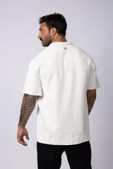 Chomba de manga corta con cuello polo, confeccionada en tejido de punto acanalado de textura pesada. Presenta un calce relajado y cuenta con una pequeña etiqueta distintiva en el ruedo.