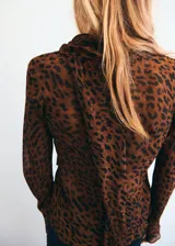 Blusa de manga larga acampanada con estampado de leopardo, cuello redondo y detalle de fular integrado en el cuello.