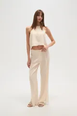 Pantalon de corte recto confeccionado en viscosa, color natural, con detalle de costuras desflecadas a lo largo de las piernas.