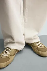Zapatilla de estilo retro con cordones, confeccionada en una combinación de piezas de tela y cuero con acabado de gamuza. Cuenta con suela dentada en contraste.