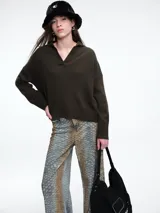 Sweater de punto color verde oliva, con cuello polo abierto en V, manga larga con hombros caídos y terminaciones acanaladas en puños y ruedo.