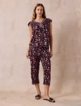 Conjunto de pijama marca René Rofé, compuesto por remera de escote en V con botones y pantalón capri con cintura elastizada, ambos en tejido soft estampado con flores rojas sobre fondo negro.