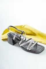 Sandalias de cuero negro con tiras finas cruzadas, taco cuadrado y hebilla lateral.