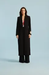 Tapado negro Natalia Antolín modelo Lavanda, de corte largo y silueta envolvente, con solapas amplias y etiqueta con la marca estampada en el puño.