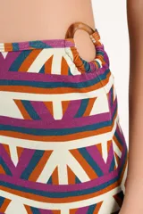 Falda larga de licra con diseño estampado geométrico multicolor, drapeado asimétrico y detalle de argolla en la cintura.
