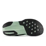 Championes de running New Balance Rebel V5 para mujer, color negro y morado oscuro con detalles en gris y suela gruesa en verde menta. Presentan tecnología de entresuela FuelCell y logo 'N' en el lateral.