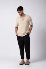 Camisa de punto de manga corta con cuello tipo bowling y cierre frontal de botones. Presenta un diseño texturizado con franjas verticales y detalles de contraste en blanco en los bordes de las mangas.