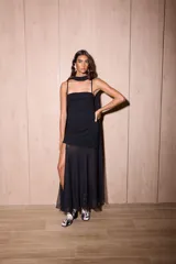 Vestido largo negro confeccionado en crepé y gasa, de corte al cuerpo con escote recto, tiritas finas y falda larga semitransparente con tajo lateral pronunciado. Incluye accesorio tipo corbatín a juego.