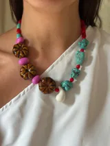 Collar corto con cuentas de cerámica, acrílico, cristales checos y piedras reconstituidas en tonos turquesa, marrón, rosa y rojo. Cierre con cadena de acero quirúrgico y gancho para regular el largo.