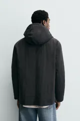 Parka técnica de corte relajado con interior ligeramente acolchado. Presenta cuello subido con capucha ajustable, cierre frontal con cremallera oculta por solapa con botones a presión, y cuatro bolsillos frontales de plastrón con solapa. Incluye cintura ajustable con cordón interior, puños con rib y aberturas laterales con cremallera en el bajo.