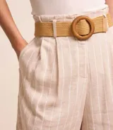 Short clochard de tiro alto, confeccionado en viscolino con estampado de rayas verticales. Incluye trabillas en la cintura y cinturón de paja con hebilla de madera.