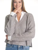Buzo de tejido de punto acanalado color gris, con escote en V y lentejuelas incrustadas. Presenta un efecto combinado con cuello y puños de camisa blanca asomando por debajo.