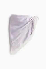 Pañuelo triangular de satén color lila con ribete de encaje blanco en los bordes y diseño para atar.