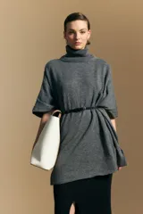 Poncho de tejido de punto color gris, con cuello alto y mangas amplias de diseño holgado.