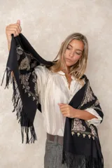 Pashmina de tela densa y suave, con caída pesada y diseño bordado con motivos florales en tonos dorados y beige. Presenta terminaciones con flecos en los extremos.