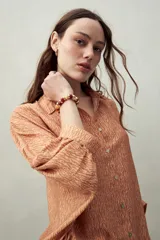 Camisa estampada con figuras geométricas en tonos azul, marrón y beige. Corte relajado, manga tres cuartos y botones al frente.