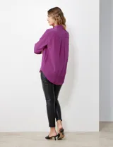 Camisa de satén color violeta, con cuello clásico, cierre frontal con botones, manga larga con puños anchos abotonados y bolsillo aplicado en el pecho.