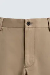 Pantalón chino de corte regular fit, confeccionado en tejido de algodón con elasticidad. Presenta bolsillos frontales, bolsillos traseros de vivo y cierre frontal con cremallera y botón.