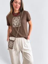 Remera marrón de manga corta y cuello redondo, con estampado floral en un recuadro claro en el frente.