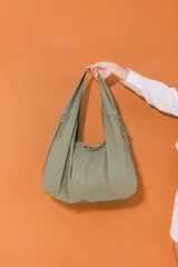 Bolso deportivo tipo duffel bag de nylon color verde oliva, con asas de mano y correa ajustable para llevar al hombro.