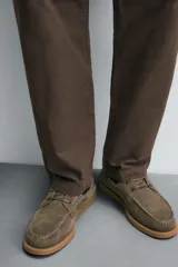 Zapato náutico color verde oliva, confeccionado en cuero serraje, con cordones de cuero y suela plana.