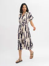 Vestido midi camisero de viscosa color beige con estampado abstracto en azul marino, manga corta, cuello camisero, cierre frontal con botones y lazo ajustable en la cintura.