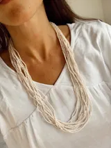 Collar de múltiples vueltas compuesto por varias hileras de mostacillas pequeñas en color marfil.