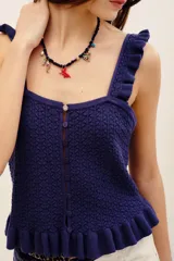Top de punto color azul marino, con tirantes anchos con volados, escote cuadrado y cierre frontal con botones. Presenta un diseño ajustado con detalles de volados en el ruedo.