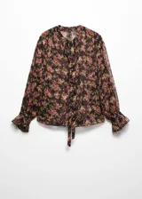 Blusa de gasa semitransparente con estampado floral en tonos rosa, verde y negro. Tiene cuello en V con lazo, cierre frontal con botones, mangas largas abullonadas con puños elásticos y corte recto.