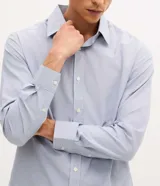 Camisa de vestir para hombre, de manga larga y calce clásico, confeccionada en tricolina de algodón y poliéster, con diseño de cuadros grid en tono celeste claro. Presenta cuello camisero, cierre frontal con botones y puños ajustables con botón único.