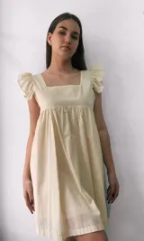 Vestido corto amarillo pastel con escote cuadrado y mangas cortas abullonadas. Diseño holgado con falda fruncida. 