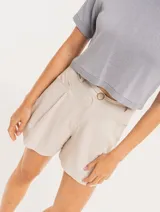 Short color beige de lino con tiro alto, elástico en la pretina trasera, cierre delantero con botón, tablas en el frente, bolsillos delanteros y dobladillo invisible.