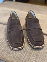 Mocasines de gamuza color marrón chocolate, con detalle de costuras en contraste en la suela.