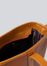 Bolso tipo tote de cuero sintético color marrón, con doble asa corta para llevar al hombro. Tiene un compartimento principal con cierre y un bolsillo interno.