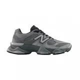 Championes New Balance modelo 9060, de estilo chunky, en tonos grises con detalles oscuros. Confeccionados con paneles de malla, gamuza y cuero sintético, presentan una distintiva entresuela esculpida y el logotipo "N" característico en los laterales.