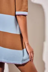 Vestido corto de tejido de punto con diseño de rayas horizontales anchas en color rosa y marrón. Presenta cuello redondo, mangas cortas y un detalle de borde en color naranja vibrante en las terminaciones de las mangas y el ruedo.