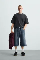 Camiseta gris de corte cuadrado y holgado, con cuello redondo y mangas cortas.