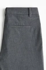 Pantalón sastrero gris oscuro de tiro alto, con corte acampanado, trabillas para cinturón y cierre frontal con cremallera y gancho oculto.
