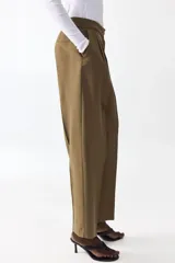 Pantalón de tiro alto de sarga color verde militar, con corte holgado y diseño barrel. Presenta pinzas y pliegues en la parte delantera y trasera, bolsillos al bies y bolsillos traseros decorativos.