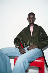 Chaqueta estilo bomber de efecto piel en color verde oliva, con cuello solapa, cierre frontal con cremallera, mangas largas y bajo elástico.