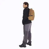 Mochila de 25 litros marca Merrell, modelo Trout Basic, en color mostaza. Confeccionada en poliéster Oxford con recubrimiento de poliuretano, presenta un compartimento principal con cierre, bolsillos laterales de malla con correas de compresión y una cinta frontal con bucles.